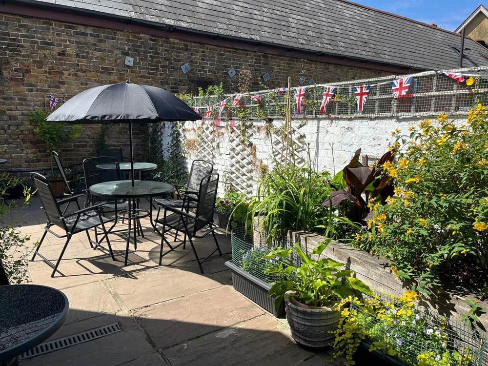 The Club garden, with tables, parasols and planted borders